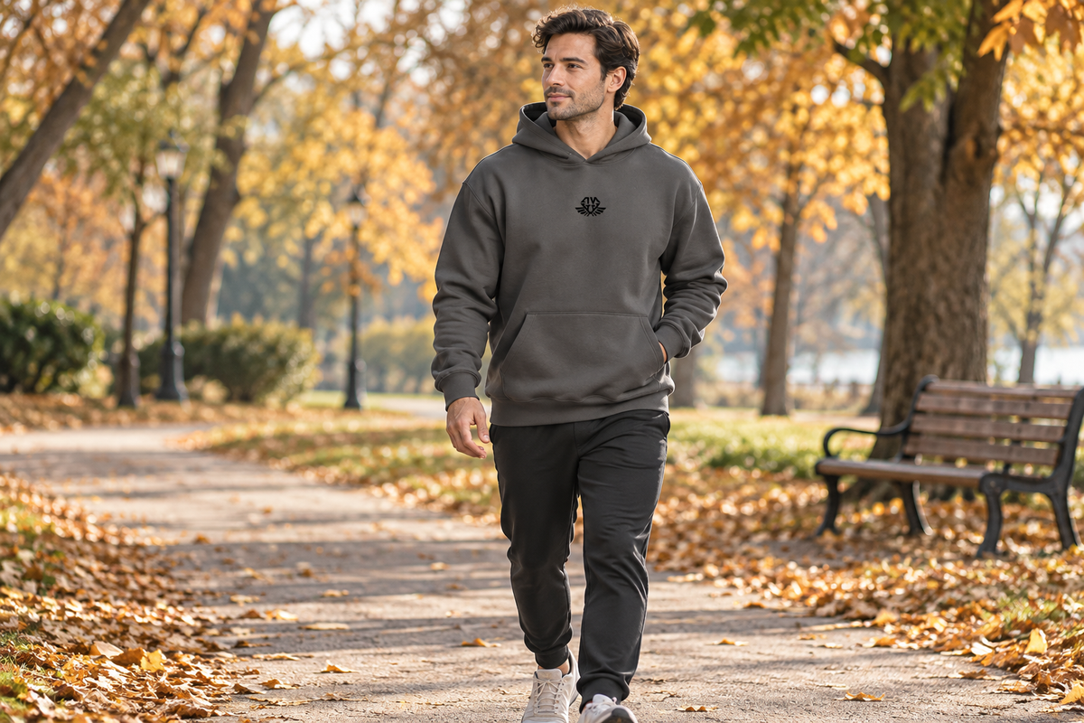 AI-generated scene of a man wearing a dark gray ANVTT hoodie on an autumn park walk.