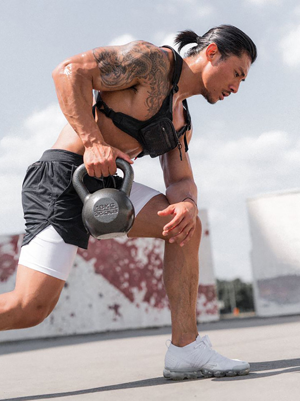 Athletic man performing kettlebell deadlift wearing Anvtt men's black 
gym shorts – functional training activewear for strength and HIIT workouts