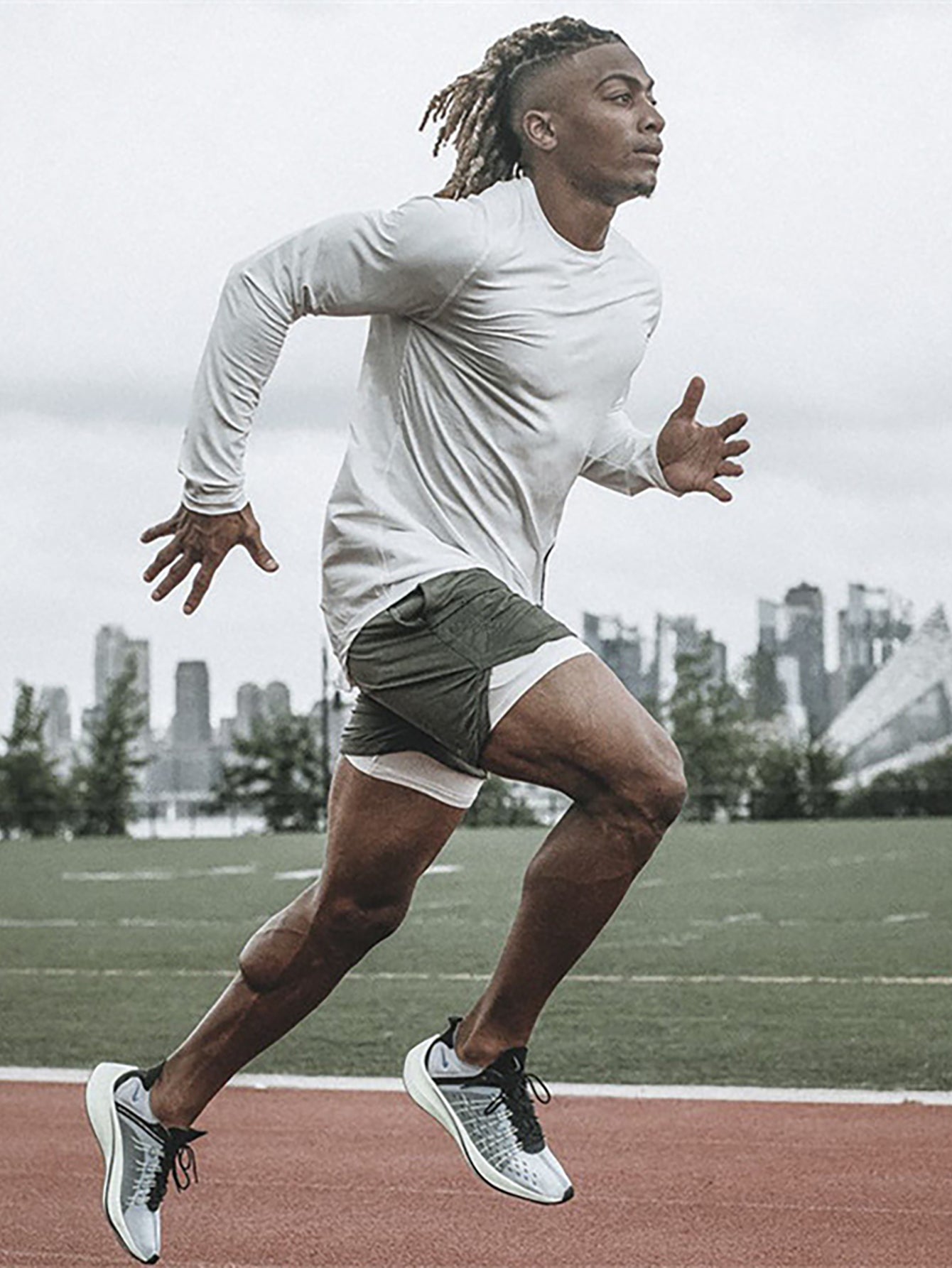 Male athlete sprinting on outdoor track wearing Anvtt men's long sleeve 
running shirt and lightweight gym shorts – performance activewear for 
running and cardio training in USA